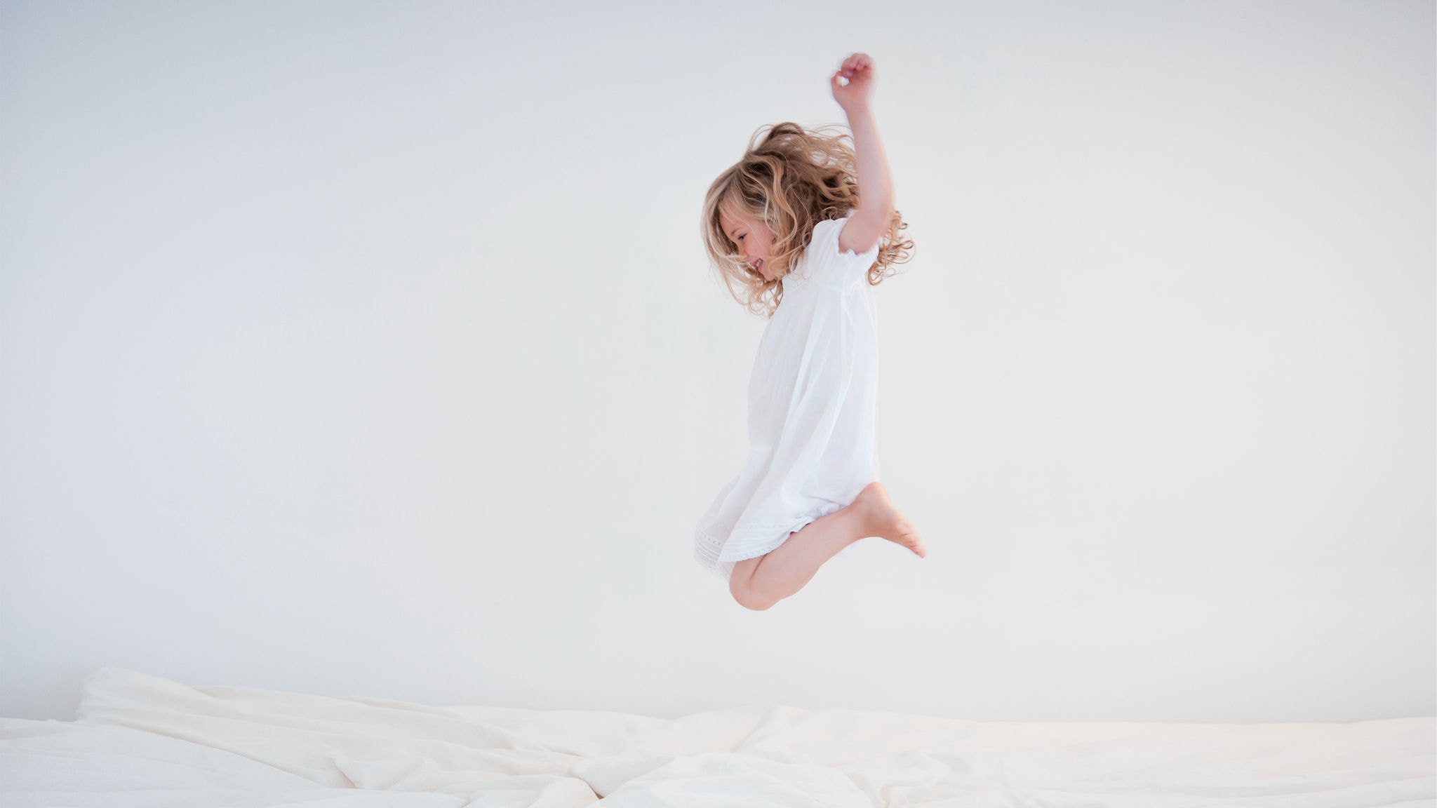 Bambino che salta sul letto godendosi l'aria fresca e pulita